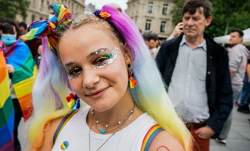 Uma pessoa com cabelo tingido e bandeiras arco-íris no desfile do Dublin Pride