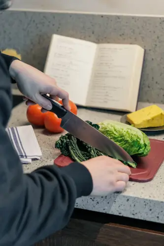 A bleisure traveller slices kale on a chopping board in an aparthotel