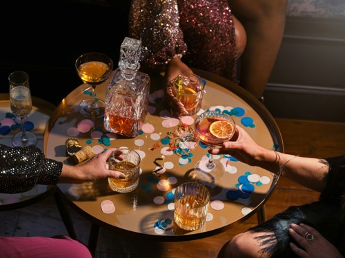 Bebidas de Natal numa mesa redonda com mãos a alcançar